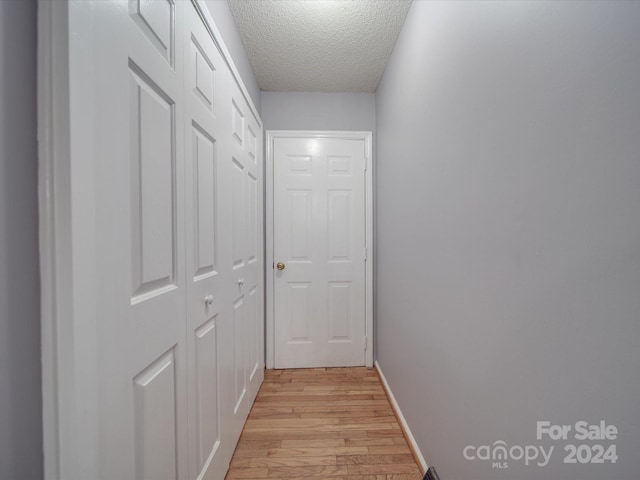 hall with a textured ceiling and light hardwood / wood-style floors