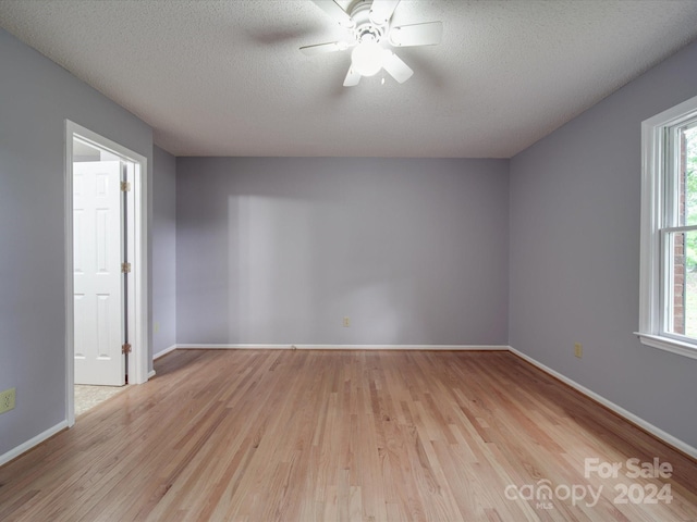 spare room with light wood-type flooring, a textured ceiling, and ceiling fan