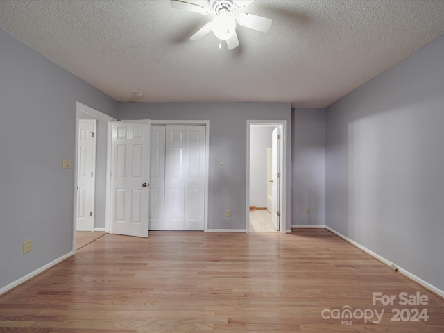 unfurnished bedroom with light wood-type flooring, connected bathroom, a textured ceiling, and ceiling fan