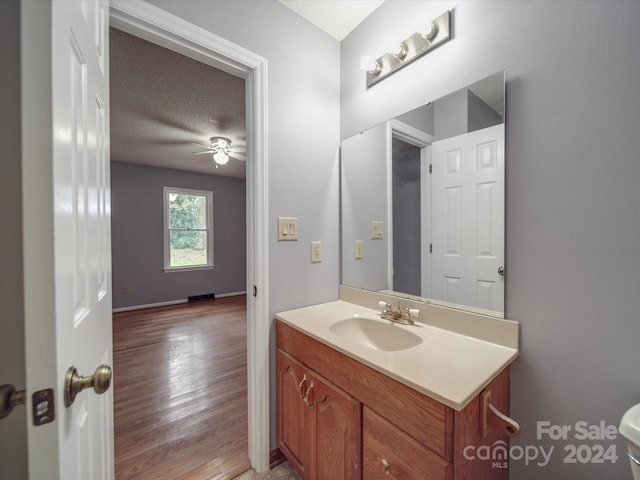 bathroom with a textured ceiling, wood-type flooring, vanity, and toilet