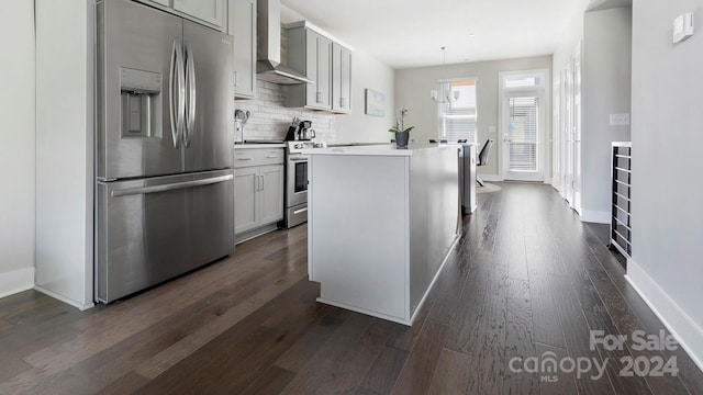 kitchen featuring pendant lighting, a kitchen island with sink, wall chimney exhaust hood, appliances with stainless steel finishes, and dark hardwood / wood-style flooring