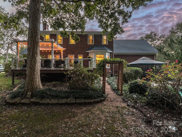 back house at dusk featuring a deck