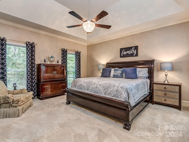 carpeted bedroom with ceiling fan, a raised ceiling, and ornamental molding