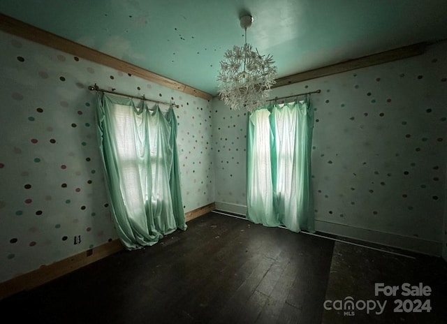 empty room with a notable chandelier and dark hardwood / wood-style flooring