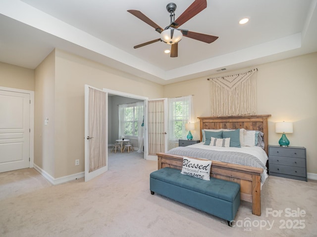 carpeted bedroom with a tray ceiling and ceiling fan