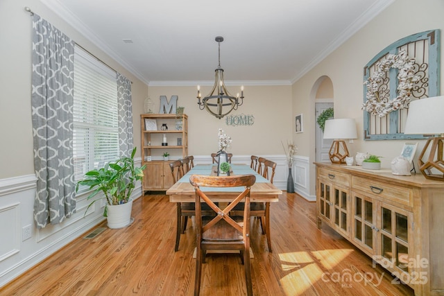 dining space with crown molding, a chandelier, and light hardwood / wood-style floors