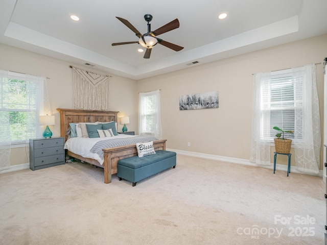 carpeted bedroom with ceiling fan and a tray ceiling