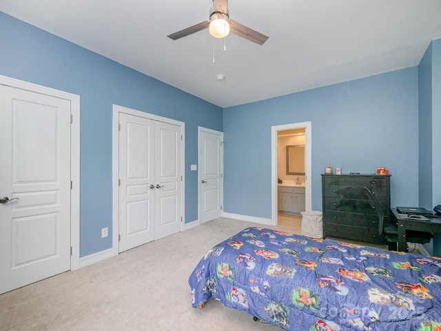 bedroom featuring ensuite bathroom, sink, carpet flooring, two closets, and ceiling fan