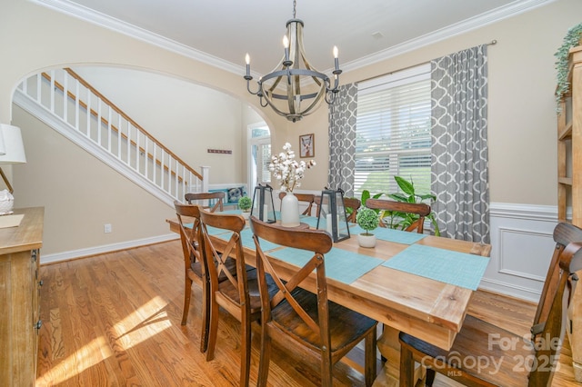 121 Canvasback Rd, Mooresville, NC 28117 - dining area featuring a chandelier, arched walkways, light wood-style floors, ornamental molding, and stairs