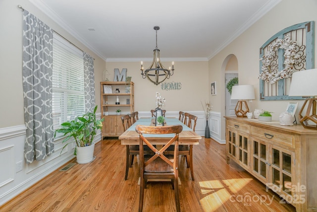 121 Canvasback Rd, Mooresville, NC 28117 - dining area featuring ornamental molding, a chandelier, arched walkways, light wood-type flooring, and wainscoting