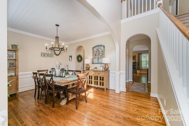 121 Canvasback Rd, Mooresville, NC 28117 - dining area with light wood-style floors, arched walkways, crown molding, a wainscoted wall, and a chandelier