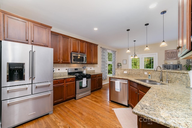 121 Canvasback Rd, Mooresville, NC 28117 - kitchen with stainless steel appliances, light wood-style flooring, backsplash, decorative light fixtures, and light stone counters