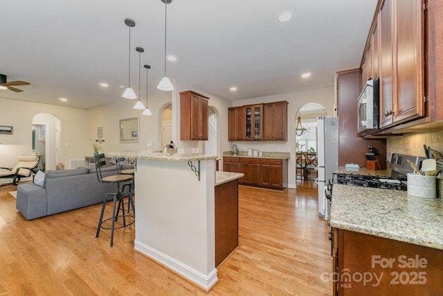 121 Canvasback Rd, Mooresville, NC 28117 - kitchen featuring arched walkways, stainless steel microwave, a kitchen bar, a peninsula, and open floor plan