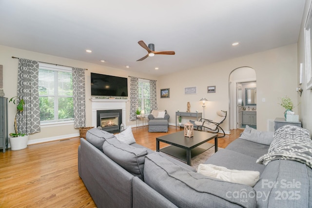 121 Canvasback Rd, Mooresville, NC 28117 - living area with a glass covered fireplace, ceiling fan, light wood-type flooring, recessed lighting, and arched walkways
