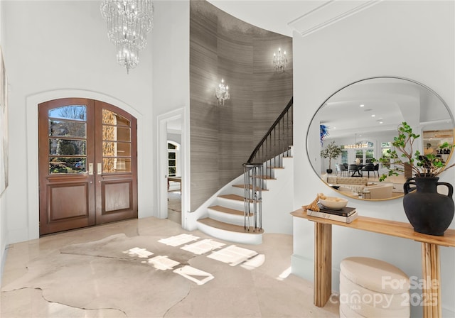 foyer with an inviting chandelier, a towering ceiling, and french doors