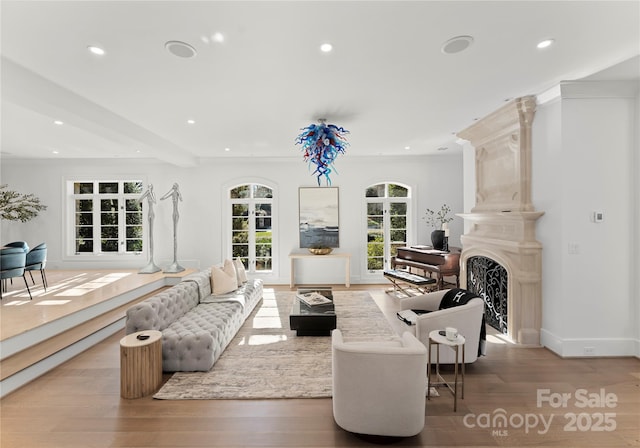 living room featuring beamed ceiling, crown molding, a high end fireplace, and light hardwood / wood-style flooring