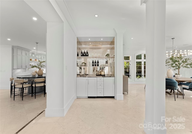 bar with hanging light fixtures, ornamental molding, a chandelier, and decorative backsplash