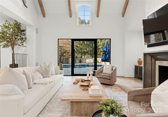 living room with french doors, a towering ceiling, beam ceiling, and light hardwood / wood-style floors