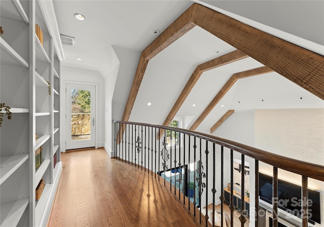 hall with wood-type flooring and vaulted ceiling with beams