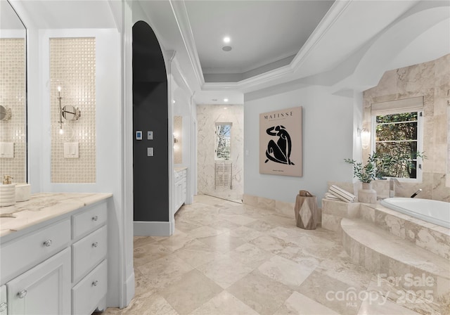 bathroom with tiled tub, crown molding, and vanity