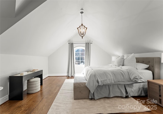 bedroom with lofted ceiling, hardwood / wood-style flooring, and an inviting chandelier