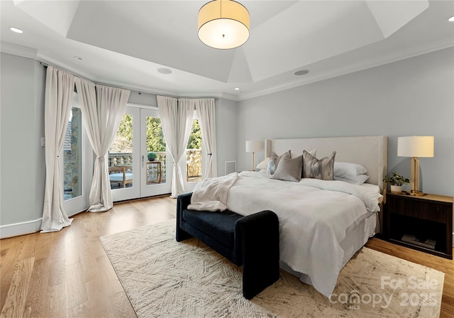 bedroom with ornamental molding, access to exterior, a raised ceiling, and light wood-type flooring