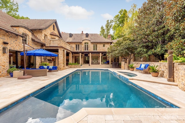 view of pool featuring an outdoor living space, an in ground hot tub, and a patio