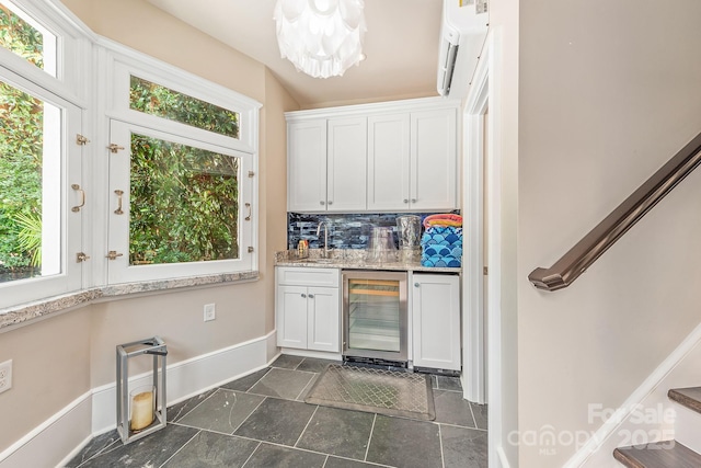 kitchen featuring sink, wine cooler, white cabinets, decorative backsplash, and a chandelier