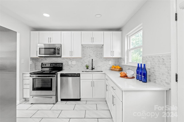 kitchen featuring decorative backsplash, white cabinetry, appliances with stainless steel finishes, and sink