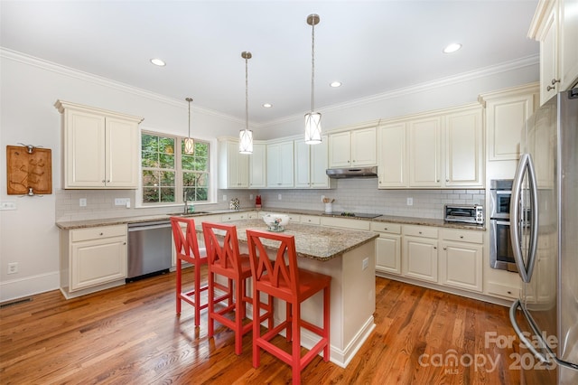 kitchen with light stone countertops, a center island, sink, stainless steel appliances, and a kitchen breakfast bar