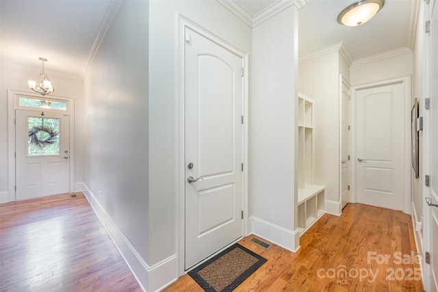 foyer entrance featuring light hardwood / wood-style flooring, crown molding, and a notable chandelier