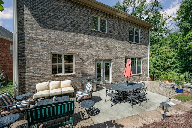 rear view of property featuring outdoor lounge area, french doors, a patio area, and exterior kitchen