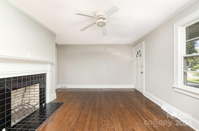 unfurnished living room featuring ceiling fan, ornamental molding, a tiled fireplace, and dark hardwood / wood-style flooring