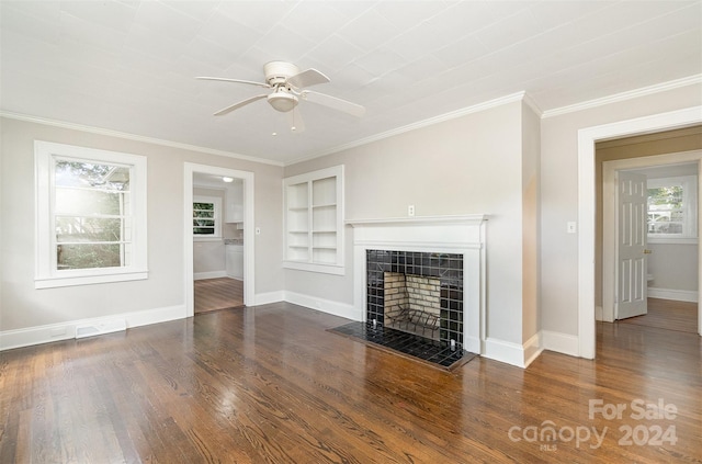 unfurnished living room featuring a tile fireplace, crown molding, dark hardwood / wood-style floors, and built in features