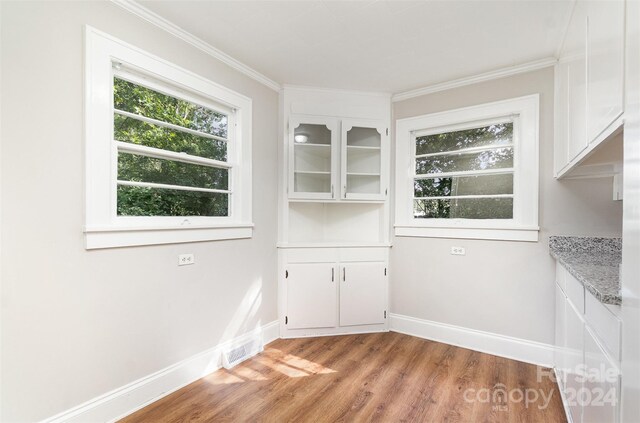 unfurnished dining area with ornamental molding and light hardwood / wood-style flooring