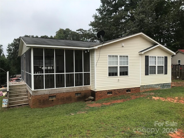 back of property featuring a lawn and a sunroom