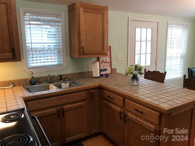 kitchen featuring kitchen peninsula, a wealth of natural light, and tile countertops