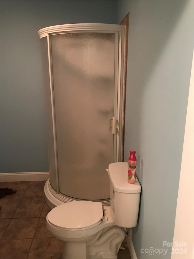 bathroom with a shower with shower door, tile patterned floors, and toilet