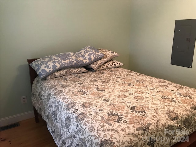 bedroom featuring electric panel and dark hardwood / wood-style flooring