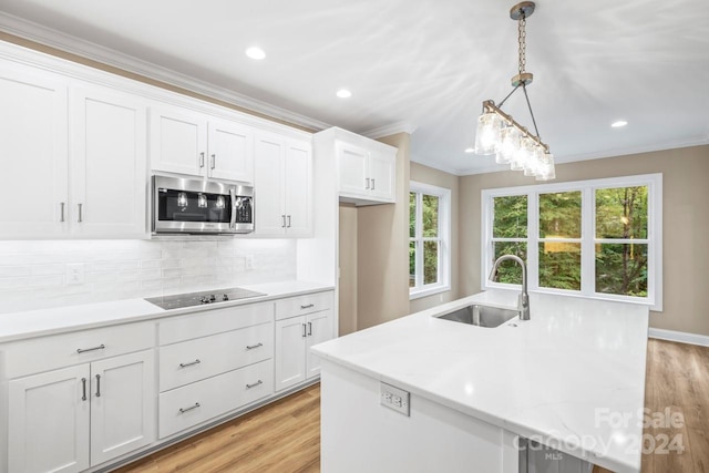 kitchen featuring hanging light fixtures, white cabinetry, sink, and light hardwood / wood-style flooring