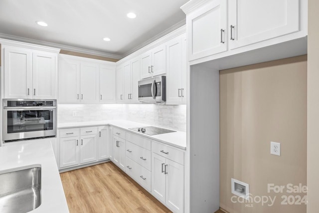 kitchen featuring white cabinets, sink, backsplash, appliances with stainless steel finishes, and light wood-type flooring