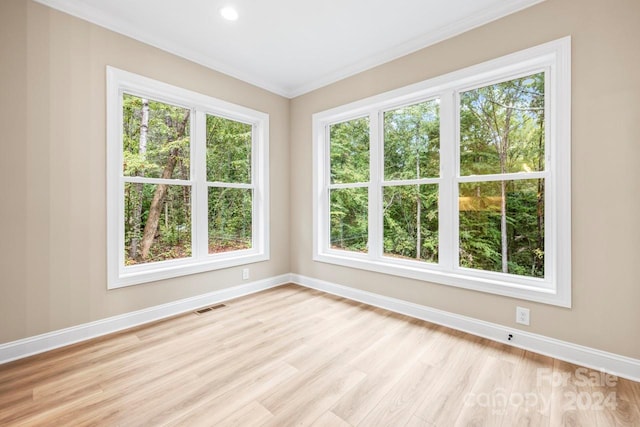 unfurnished room with light hardwood / wood-style flooring, ornamental molding, and a healthy amount of sunlight