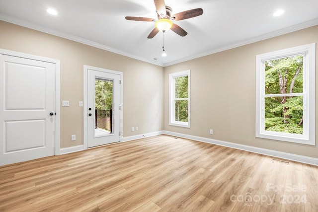 spare room featuring ceiling fan, light wood-type flooring, plenty of natural light, and crown molding