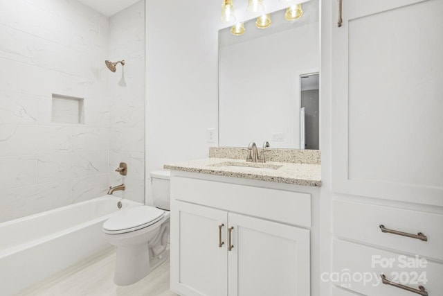 full bathroom featuring vanity, tiled shower / bath combo, and toilet