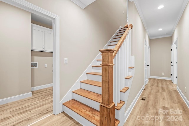 stairs featuring ornamental molding and wood-type flooring