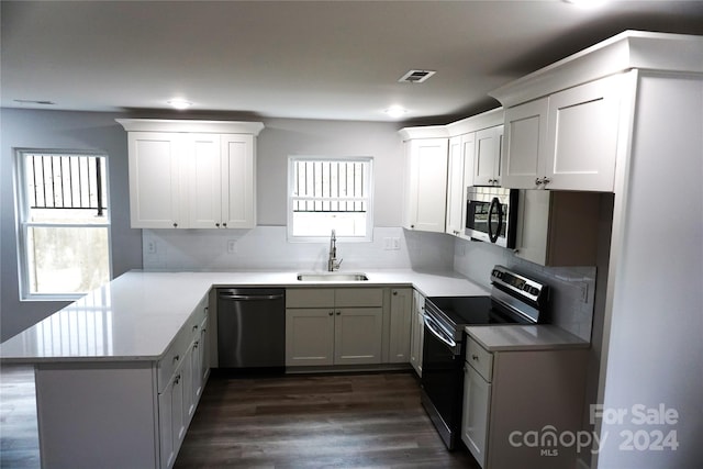 kitchen featuring stainless steel appliances, white cabinetry, kitchen peninsula, and dark wood-type flooring