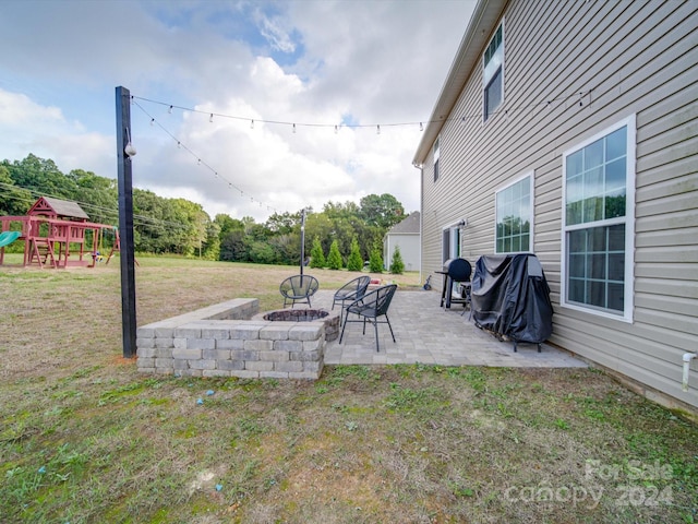 view of yard featuring a patio, a playground, and a fire pit