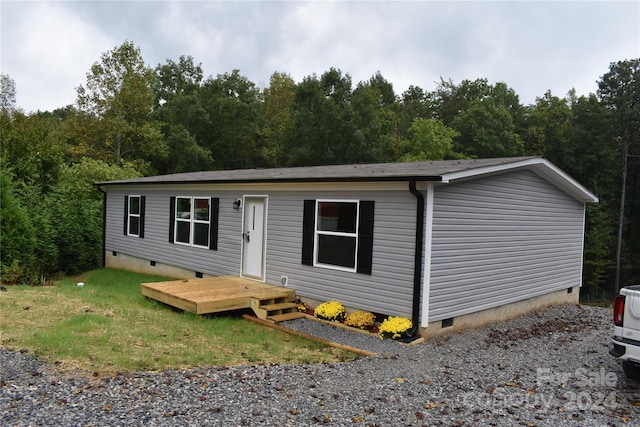 manufactured / mobile home featuring a front lawn and a wooden deck