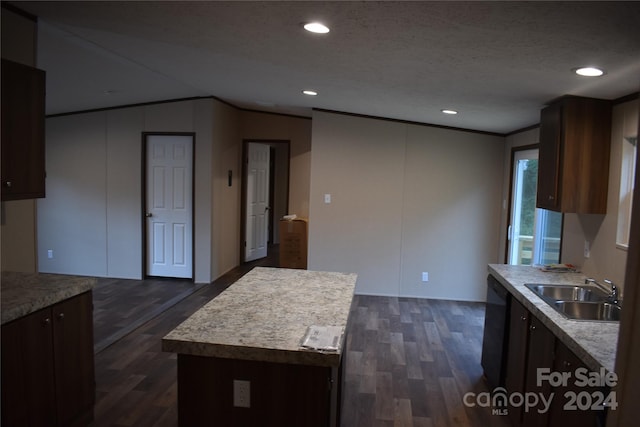 kitchen with a textured ceiling, a center island, sink, and dark hardwood / wood-style flooring