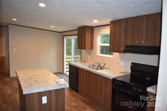 kitchen with black appliances, dark wood-type flooring, sink, range hood, and a center island